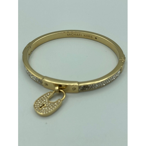 224 - MICHAEL KORS jewelled BANGLE in gold tone with jewelled padlock, complete with Michael Kors soft pou... 