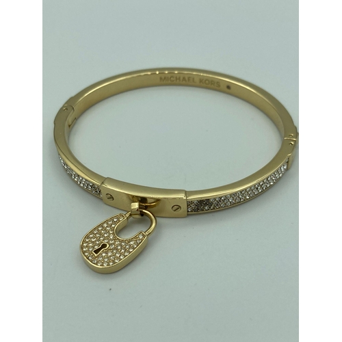 224 - MICHAEL KORS jewelled BANGLE in gold tone with jewelled padlock, complete with Michael Kors soft pou... 