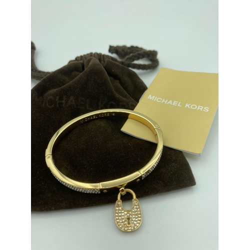 224 - MICHAEL KORS jewelled BANGLE in gold tone with jewelled padlock, complete with Michael Kors soft pou... 