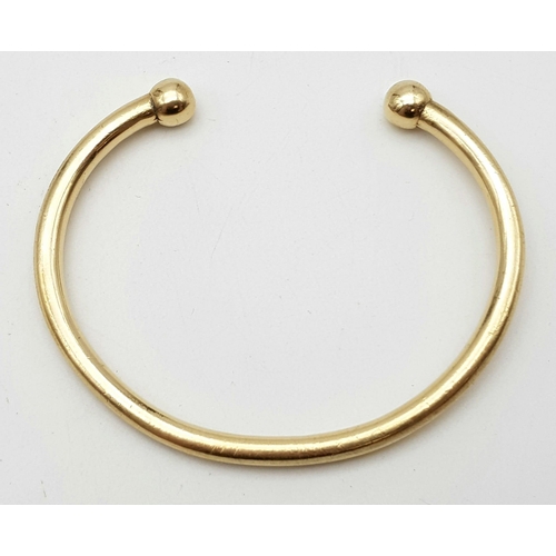 240 - A 9 K yellow gold solid torque bangle. Weight: 33.5 g.