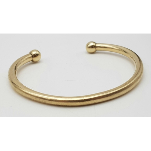 240 - A 9 K yellow gold solid torque bangle. Weight: 33.5 g.