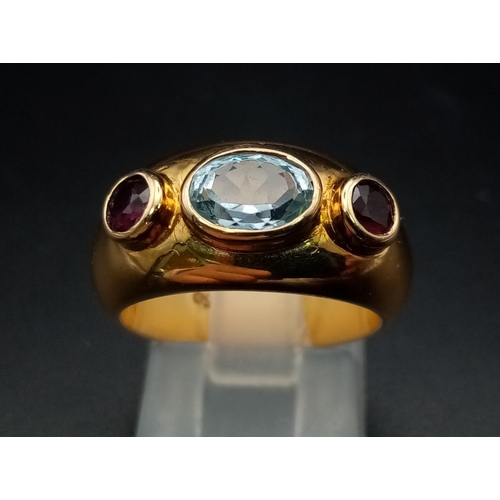 142 - AN 18K YELLOW GOLD RING WITH AQUAMARINE CENTRE STONE FLANKED EITHER SIDE BY 2 GARNETS .  9.7gms  siz... 