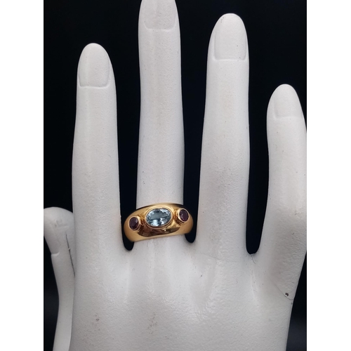 142 - AN 18K YELLOW GOLD RING WITH AQUAMARINE CENTRE STONE FLANKED EITHER SIDE BY 2 GARNETS .  9.7gms  siz... 