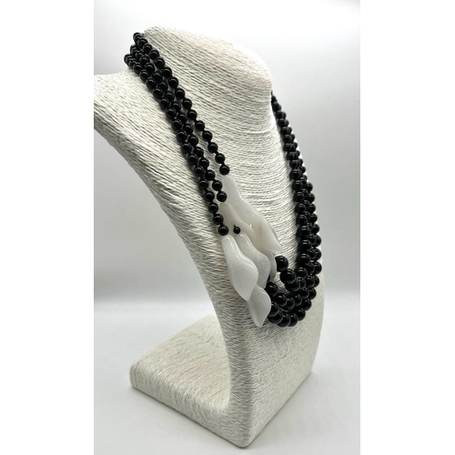 251 - A Graduated Black Onyx and White Porcelain Necklace. A mesmerising blend of onyx beads and jade flow... 