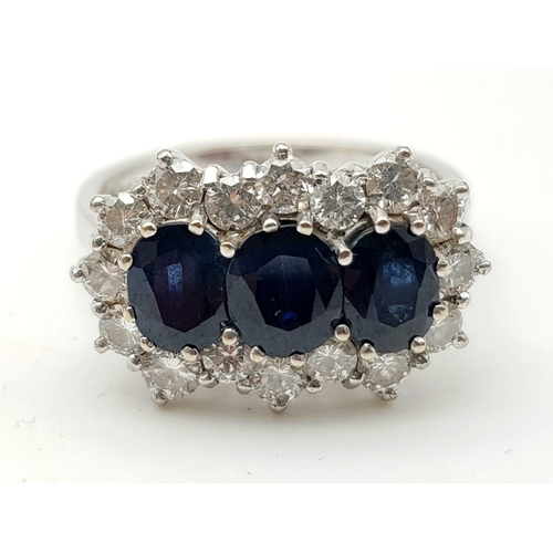 135 - An 18K White Gold Diamond and Sapphire Ring. Three central oval cut sapphires surrounded by sixteen ... 