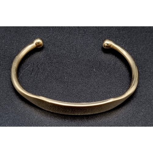 451 - A 9 K yellow gold bay torque bangle. Weight: 9.8 g.