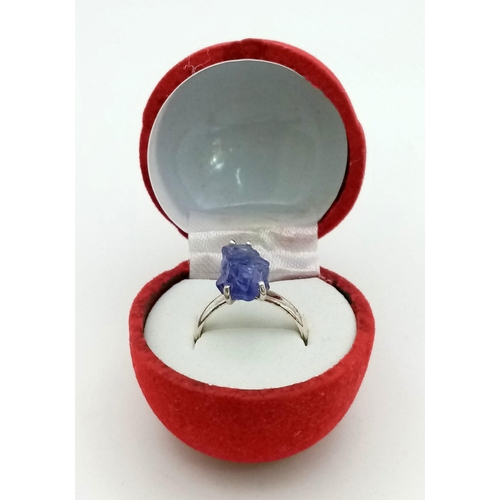 231 - A sterling silver ring with a large, natural, rough, Tanzanite, in a red rose shaped presentation bo... 