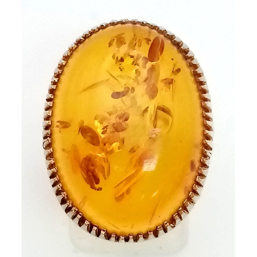 31 - A 9K Yellow Gold Amber Ring. A large natural amber cabochon set in pierced decorative gold. Wonderfu... 