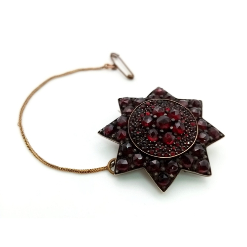 494 - An Antique Victorian Garnet Star Brooch on Yellow Metal. 
4cm. With safety chain. 10.5g total weight