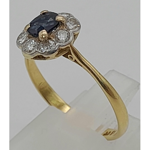 229 - An 18K Yellow Gold Sapphire and Diamond Ring. Oval cut central sapphire with a halo of nine bright d... 