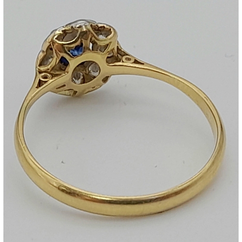 229 - An 18K Yellow Gold Sapphire and Diamond Ring. Oval cut central sapphire with a halo of nine bright d... 