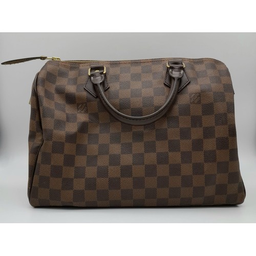 32 - A Louis Vuitton Speedy Checked Canvas Bag. Leather handles. Padlock. Red interior with flap pocket. ... 