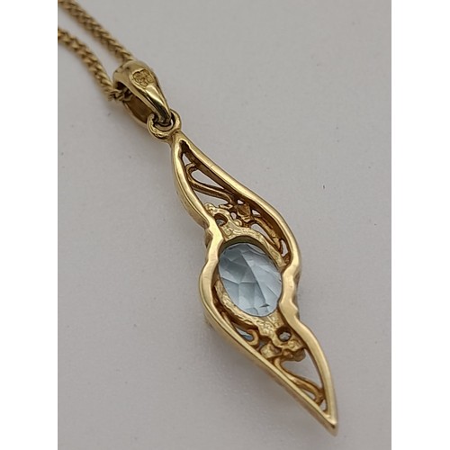 477 - A 9K Yellow Gold Topaz and Diamond Pendant on a 9K Gold Necklace. Blue oval cut topaz with a small d... 