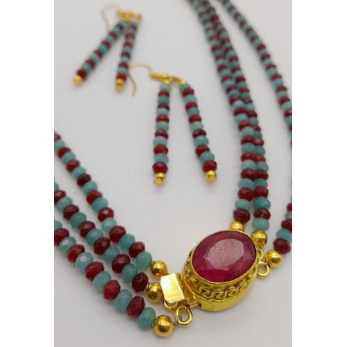 132 - A very desirable, three strand necklace with multifaceted rubies and emeralds, with a large ruby on ... 