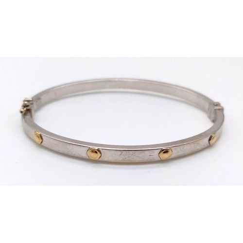 1016 - A 9K White Gold Bangle. Touches of yellow gold for decoration. Opening clasp. 6cm inner diameter. 6.... 