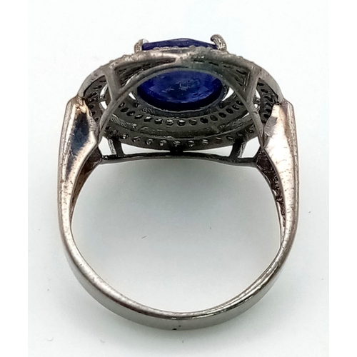 1073 - A 4.9ct Blue Oval Sapphire Gemstone Ring with .65ct of Diamonds in a Pave Setting. Size O. 4.95g tot... 