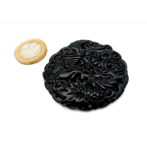 995 - A Black Jade Circular Dragon Pendant. 5cm diameter.