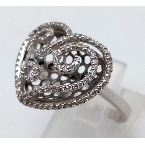 1089 - An 18 K white gold ring with a diamond encrusted heart on top.  Size: N1/2, weight: 5.34 g.