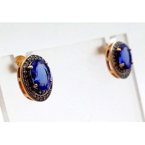 116 - A beautiful, 18 k yellow gold pair of earrings with an oval cut tanzanite surrounded by a halo of di... 