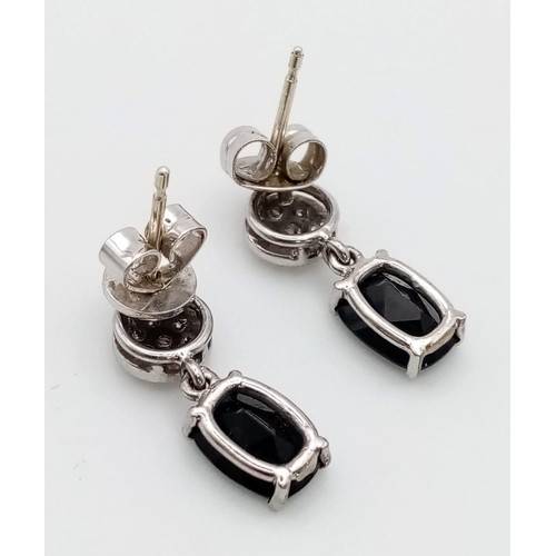 326 - An 18 K white gold pair of earrings with diamonds and an oval cut black sapphire. Drop: 15 mm, weigh... 