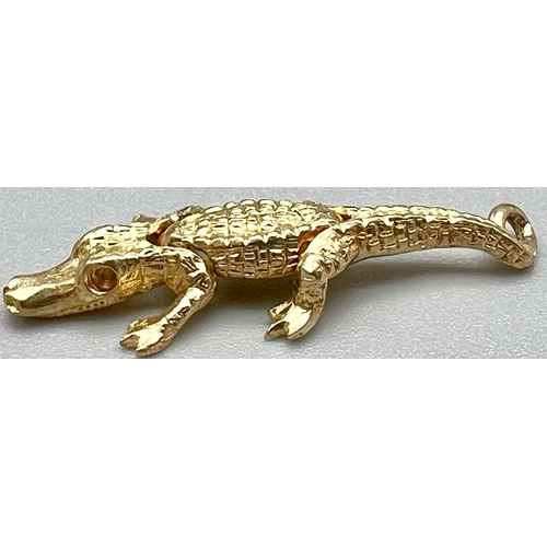 754 - A 9 K yellow gold, very detailed and articulate crocodile 
 charm. Length: 28 mm, weight: 1.6 g.