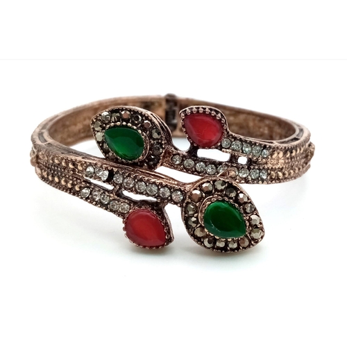 1062 - An Antique Beautifully Decorated Gem-set Hinged Serpentine Bangle. Green, red and white stone decora... 