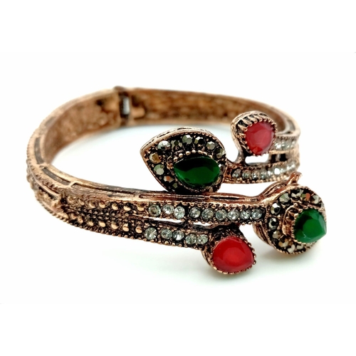 1062 - An Antique Beautifully Decorated Gem-set Hinged Serpentine Bangle. Green, red and white stone decora... 