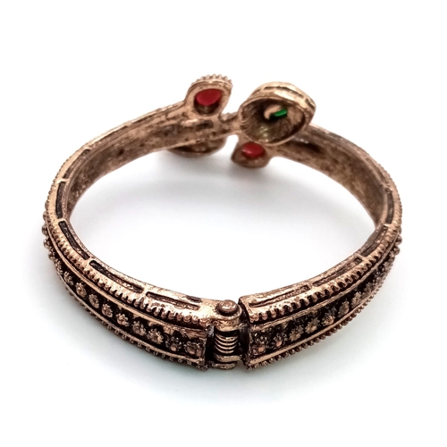 1062 - An Antique Beautifully Decorated Gem-set Hinged Serpentine Bangle. Green, red and white stone decora... 