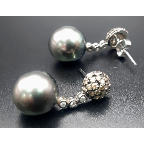 134 - An 18 K white gold pair of earrings with diamonds and Tahitian grey pearls. Drop: 25 mm, total weigh... 