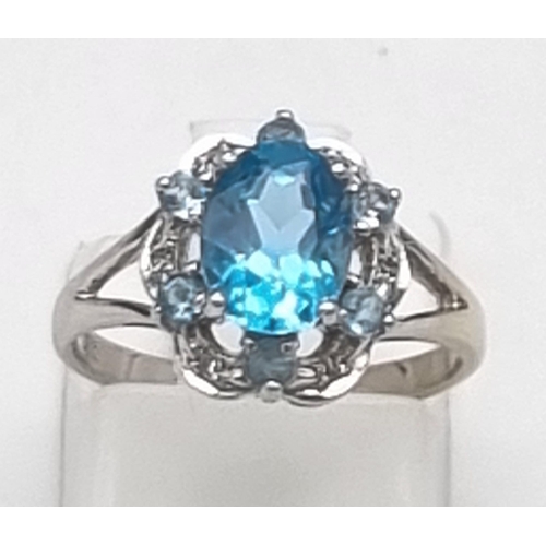 261 - A 9K White Gold Blue Topaz and Diamond Ring. A scene-stealing central blue topaz complimented with s... 