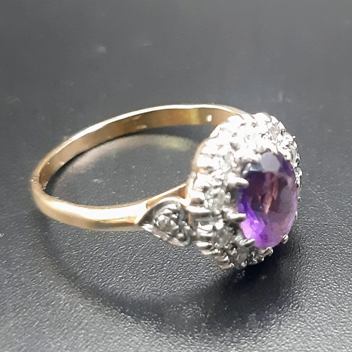 388 - An 18 K yellow gold ring with a central amethyst surrounded by diamonds.