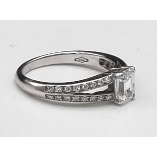 53 - An 18K White Gold Emerald Cut (0.5ct) Diamond Ring. Central emerald cut diamond with two wings of br... 