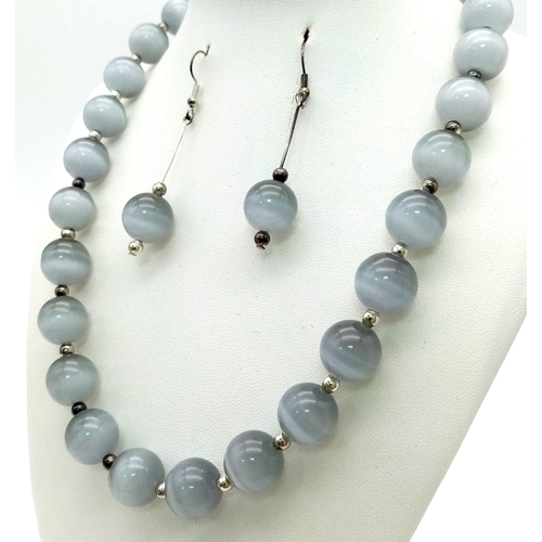 133 - A hypnotic, grey chrysoberyl cat’s eye, large beaded (14 mm), necklace and earrings set exhibiting w... 