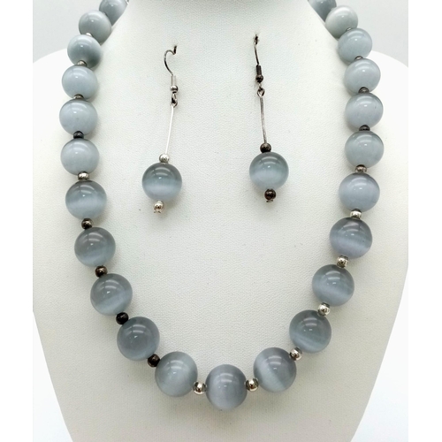 133 - A hypnotic, grey chrysoberyl cat’s eye, large beaded (14 mm), necklace and earrings set exhibiting w... 