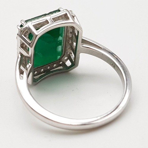 360 - A 14k White Gold Emerald and Diamond Ring. 5.5ct large central emerald surrounded with 1.1ct of Diam... 