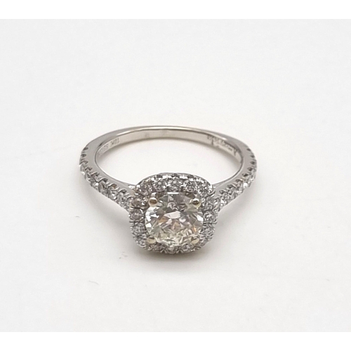 10 - An 18K White Gold Diamond Ring. A brilliant round-cut central diamond of 0.8ct surrounded by a halo ... 