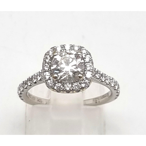 10 - An 18K White Gold Diamond Ring. A brilliant round-cut central diamond of 0.8ct surrounded by a halo ... 