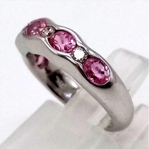 423 - An 18K White Gold Pink Tourmaline and Diamond Half-Eternity Ring. Five oval tourmalines and four rou... 