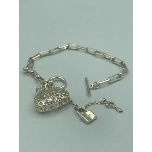 412 - Bracelet with T-bar fastening having square links with filigree purse pendant and  padlock marked 92... 