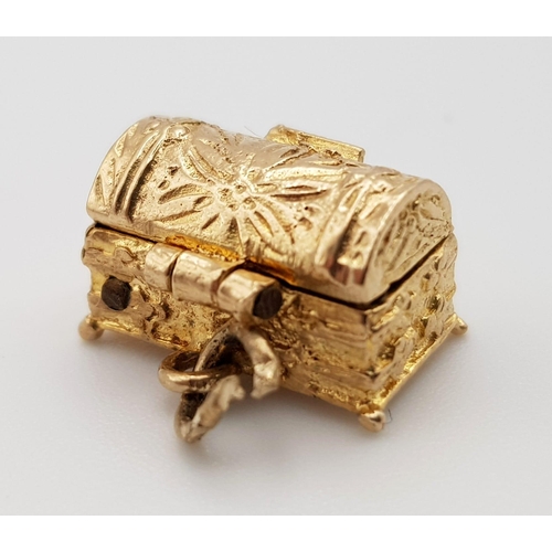 418 - A 9 K yellow gold charm in the shape of a treasure chest that opens to reveal gems. Weight: 2.8 g.