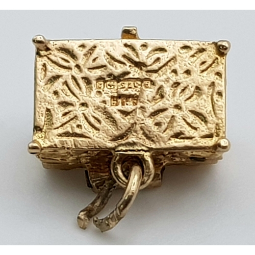 418 - A 9 K yellow gold charm in the shape of a treasure chest that opens to reveal gems. Weight: 2.8 g.