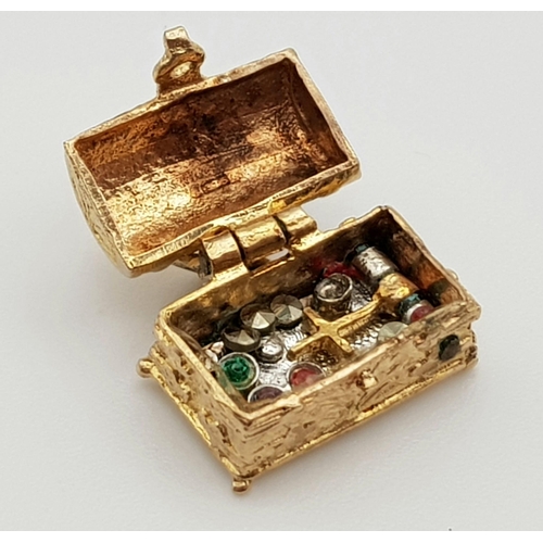 418 - A 9 K yellow gold charm in the shape of a treasure chest that opens to reveal gems. Weight: 2.8 g.