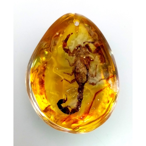 870 - A Scary Looking Scorpion Trapped In Amber Coloured Resin. Pendant or small paperweight. 6cm