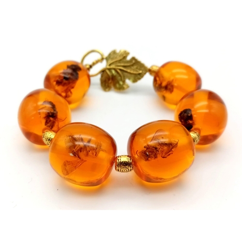 245 - A chunky, amber resin bracelet with insects (wasps, bees, flies, etc) trapped in each bead accompani... 