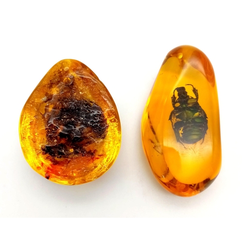 294 - Two amber resin large cabochons, one with a butterfly and the other one with another insect.