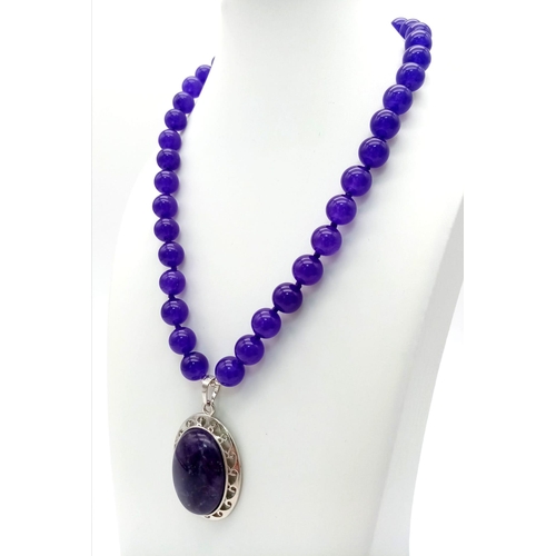 390 - An Amethyst Bead Necklace with Hanging Amethyst Oval Pendant - 5cm. Necklace - 44cm. Beads - 10mm