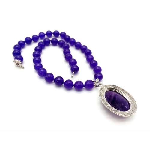 390 - An Amethyst Bead Necklace with Hanging Amethyst Oval Pendant - 5cm. Necklace - 44cm. Beads - 10mm