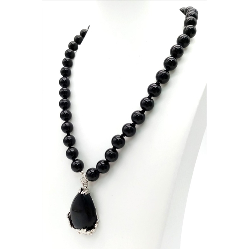 735 - A Black Onyx Agate Beaded Necklace and Teardrop Pendant. 10mm beads. Pendant - 4cm. Necklace - 44cm.