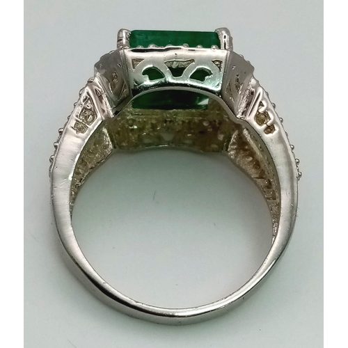 540 - A 7ct Natural Emerald ring set in 925 silver decorated with white stone surround. Size V. Comes with... 