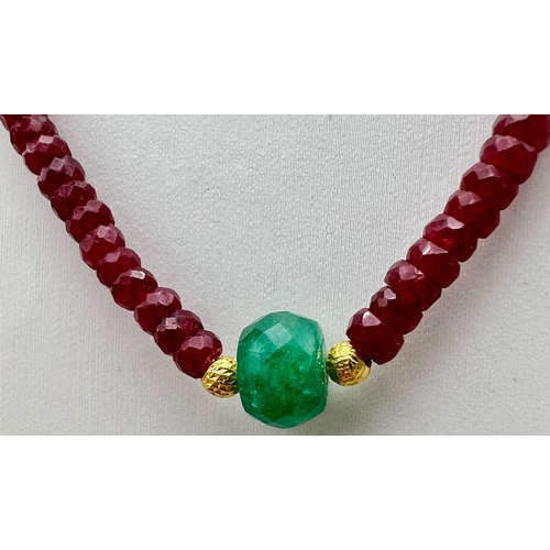 505 - A 94ct Single Strand Ruby Necklace complimented with a large Emerald Bead and gilded spaces. 925 sil... 